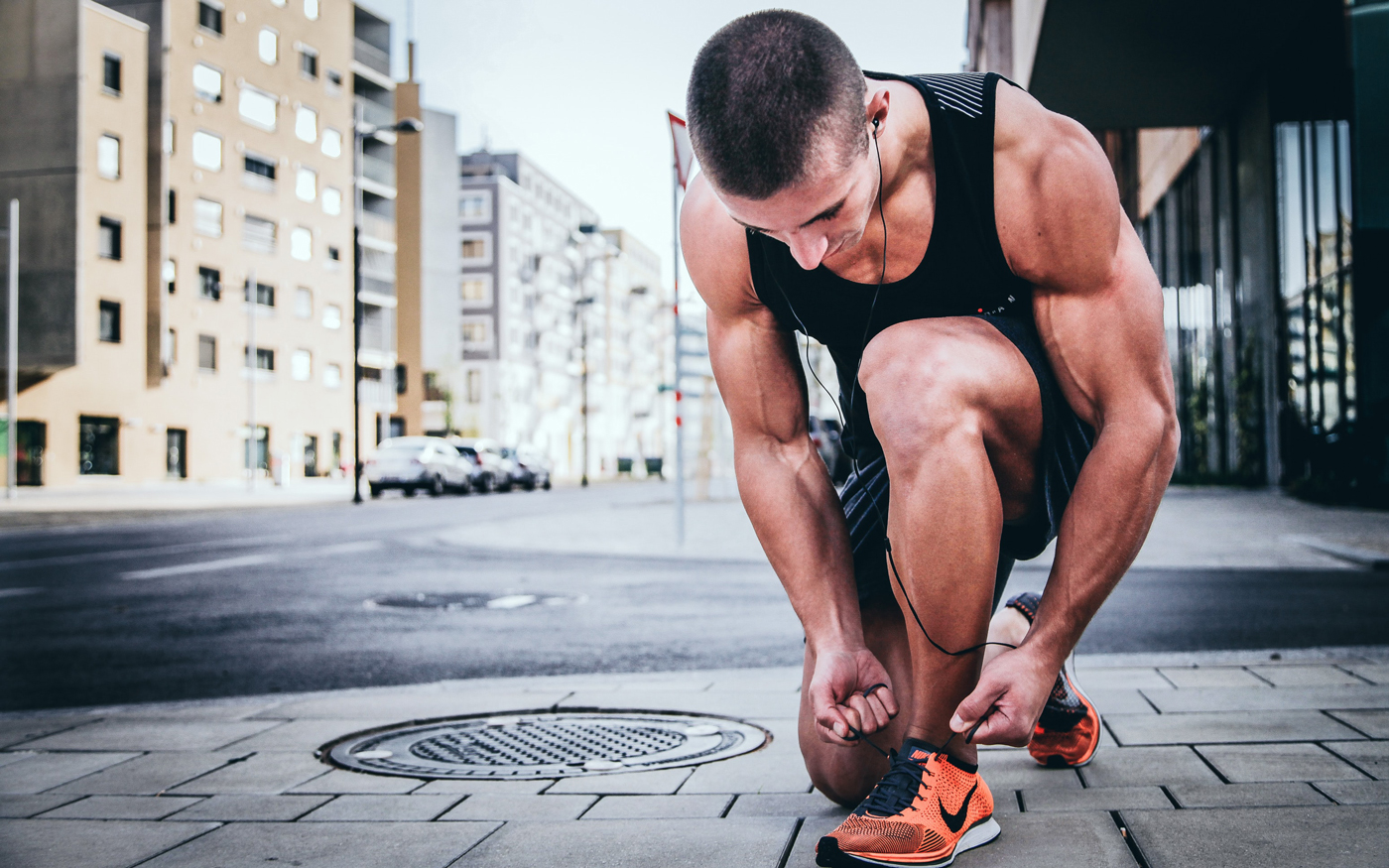 A man lacing up his shoes as he prepares for a run